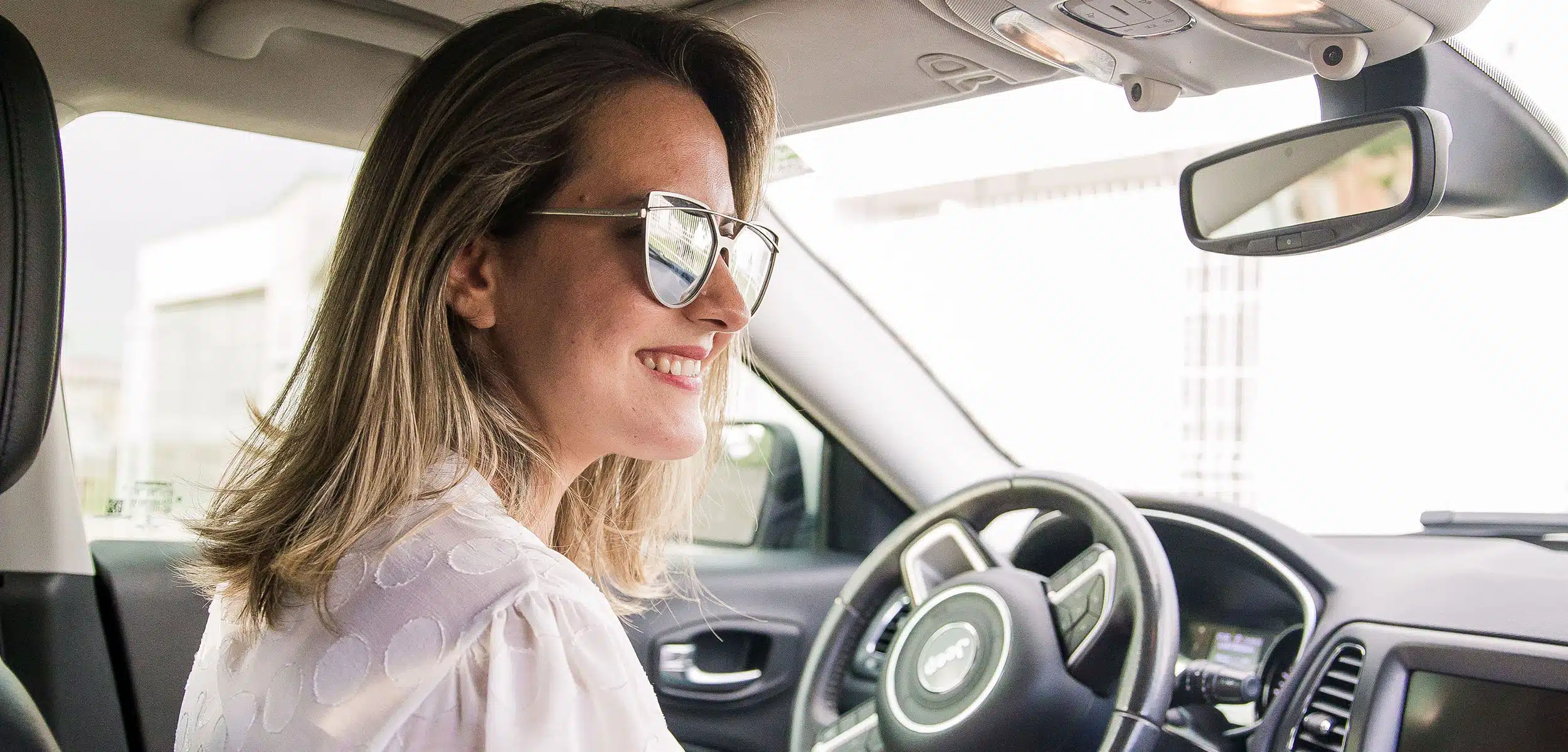 Smiling woman behind the wheel of a vehicle.